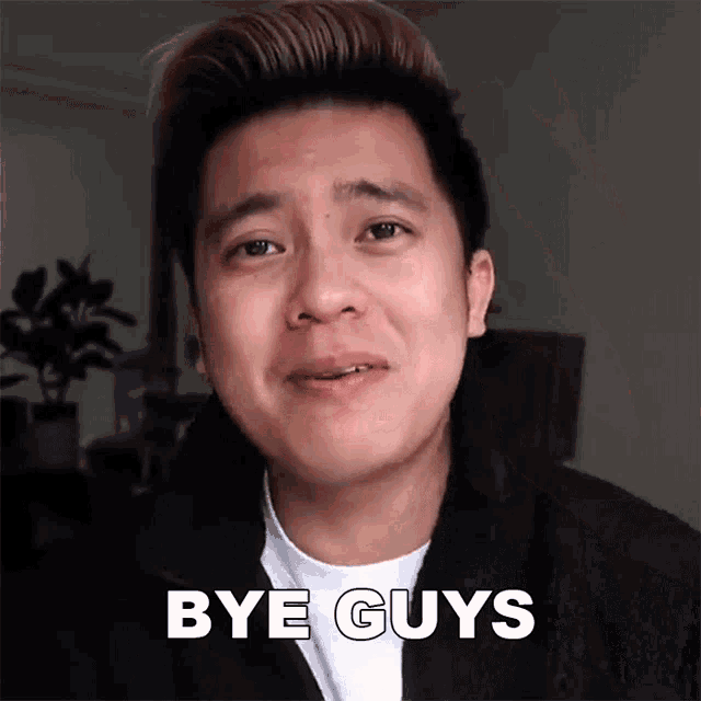 a man is crying and saying bye guys in front of a plant .
