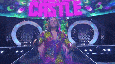 a man in a colorful outfit is walking down a stage in front of a sign that says castle .