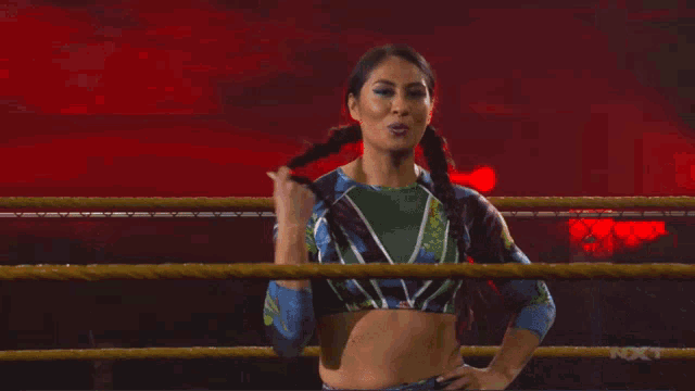 a female wrestler stands in a ring with the word nxt behind her