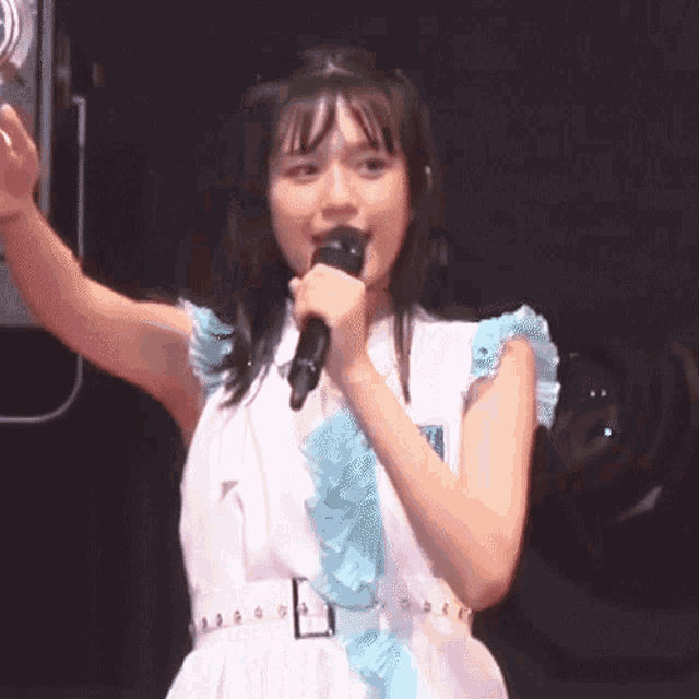 a girl in a white dress holds a microphone in her hand