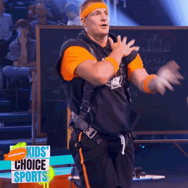 a man in an orange headband stands in front of a chalkboard that says kids choice sports on it