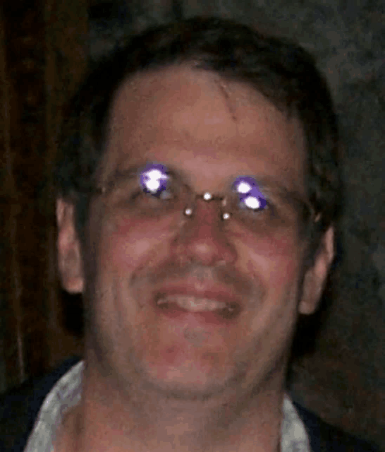 a man wearing glasses is smiling for a picture