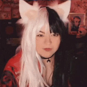 a woman wearing a wig with cat ears and a choker is sitting in front of a microphone .