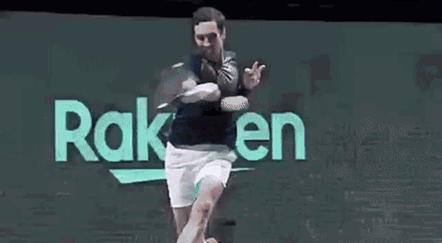 a man is swinging a tennis racket at a tennis ball in front of a rakuten sign .
