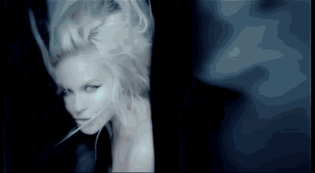 a close up of a woman 's face in a dark room with her hair blowing in the wind .