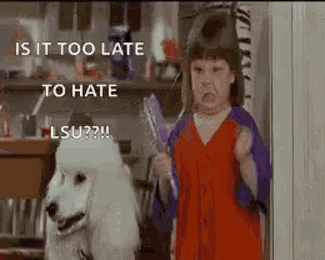 a little girl is standing next to a white poodle holding a brush and making a funny face .