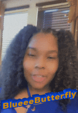 a woman with curly hair has a blue banner that says blueeebutterfly behind her