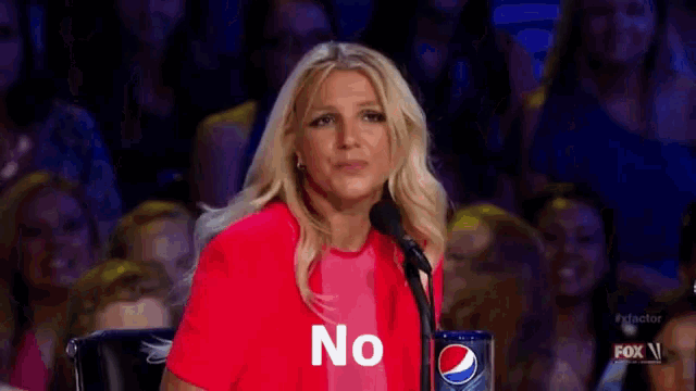 a woman is sitting in front of a microphone with the word no on her shirt .