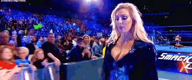 a woman is standing in front of a crowd at a wrestling match .