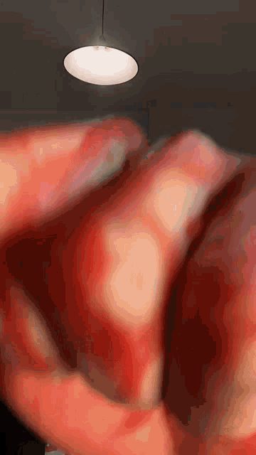 a blurred image of a person 's hand with a light hanging from the ceiling