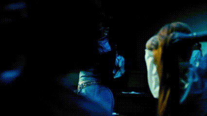 a woman in a blue dress is standing in a dark room holding a microphone .