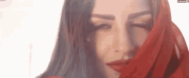 a close up of a woman 's face with a red scarf over her head