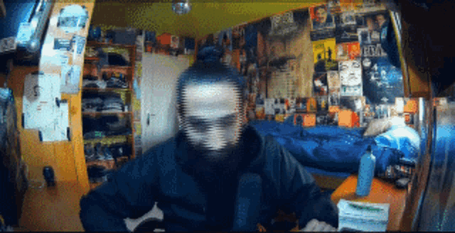 a man in a room with posters on the wall including one that says ' elvis ' on it