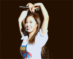 a woman making a heart shape with her hands while wearing a shirt with mickey mouse on it
