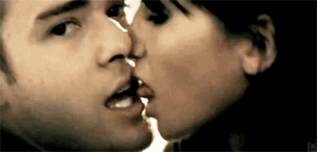 a close up of a man and woman kissing