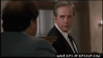 a man in a suit and tie is looking at another man in a suit and tie .