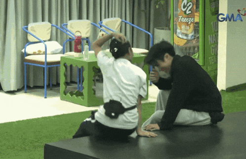 two men sit on a bench in front of a vending machine that says freeze