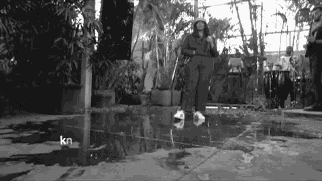 a black and white photo of a person standing in a puddle with the letters kn on the bottom
