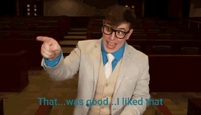 a man in a suit and tie points at the camera and says that was good
