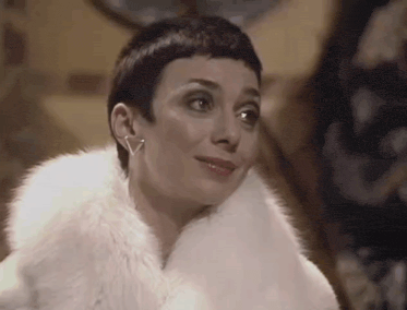 a woman with short hair is wearing a white fur coat .