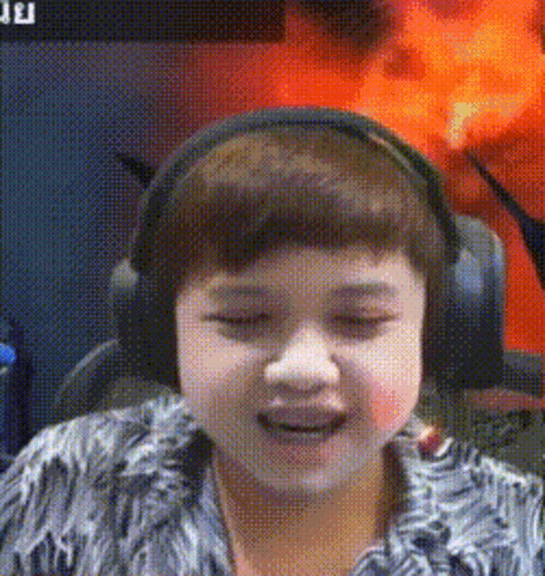 a young boy wearing headphones and a furry shirt is smiling .