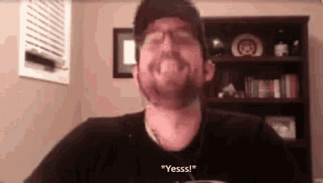 a man with a beard and glasses is making a funny face while talking on a video call .