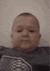 a baby is making a funny face while sitting on a bed .
