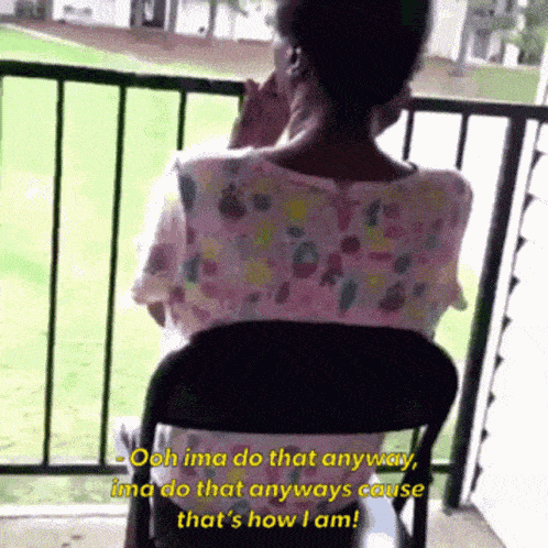 a woman sitting in a chair on a balcony talking on her phone
