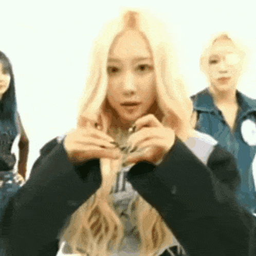 a woman with blonde hair is holding a necklace in her hands while standing next to two other women .