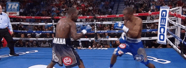 two boxers in a boxing ring with a geico sign on the ropes