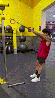 a man in a red tank top is doing a exercise in a gym
