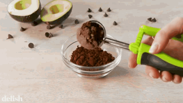 a person is scooping ice cream into a glass bowl with the word delish in the corner