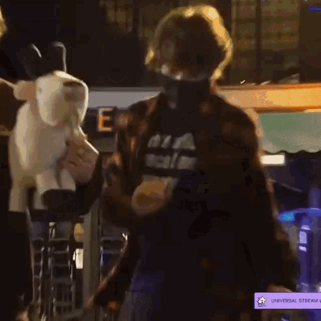 a man in a mask is holding a stuffed animal in his hands .