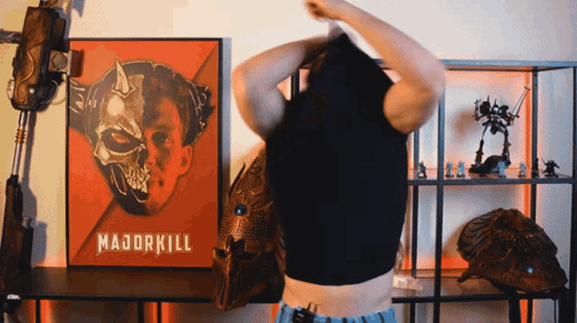 a man taking off his shirt in front of a poster that says majorkill