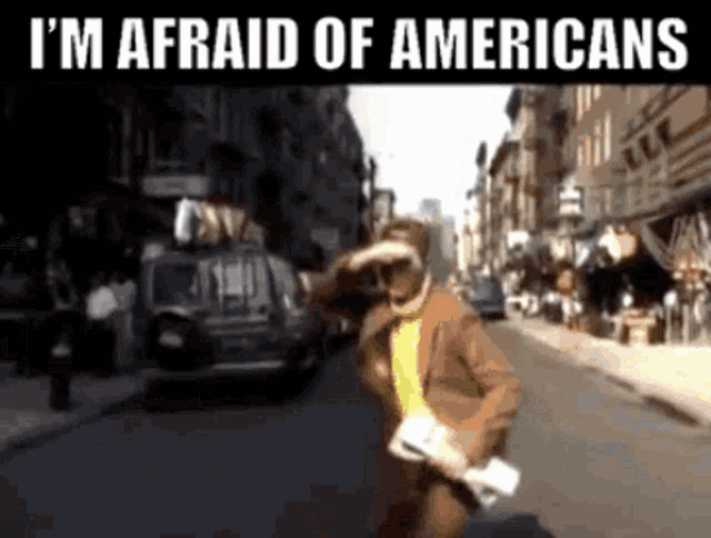 a man in a suit is running down a street with the words i 'm afraid of americans below him