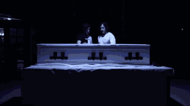 a black and white coffin with the lid open is lit up with blue light