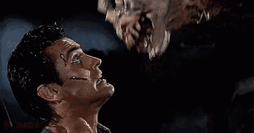 a close up of a man looking up at a monster with its mouth open
