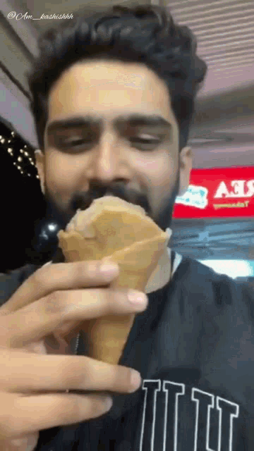a man with a beard is eating an ice cream cone in front of an ads sign