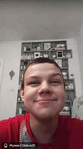 a man in a red shirt is smiling in front of a shelf with a sign that says home on it