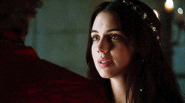 a woman with a crown on her head is looking at a man in a red coat .