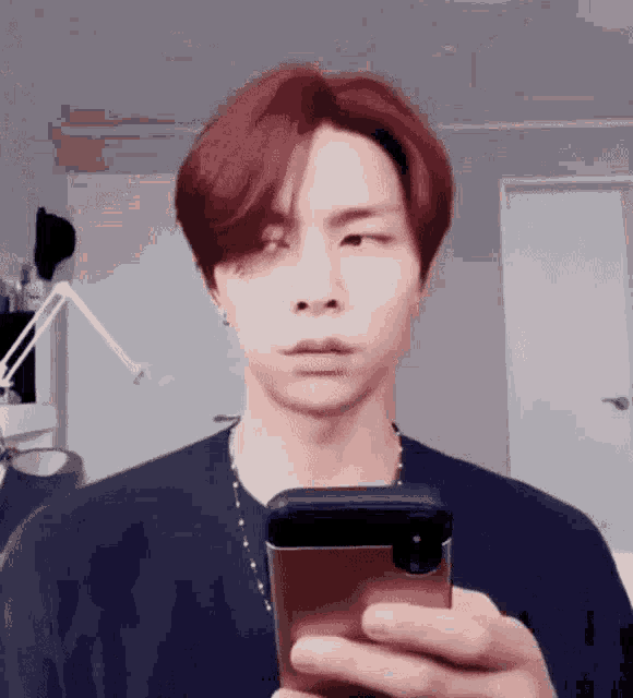 a man with red hair is taking a selfie with a cell phone .