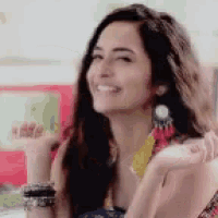 a woman wearing a necklace and earrings is smiling