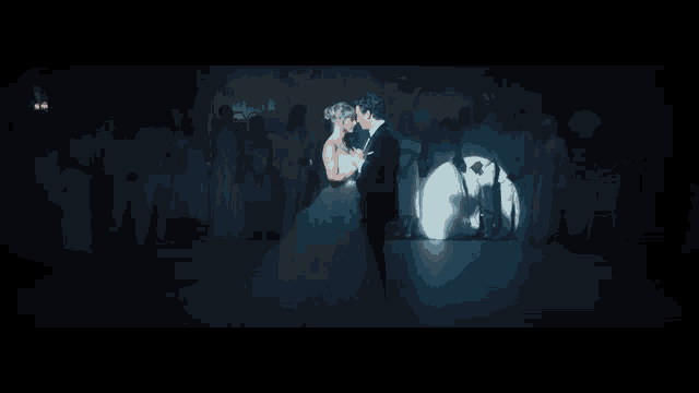 a bride and groom are dancing in a dark room