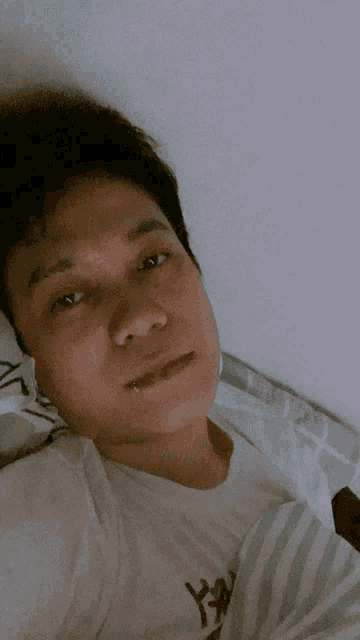 a man with a piercing in his lip is laying in a bed
