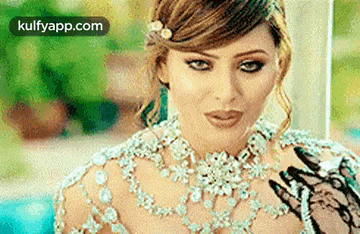 a woman is wearing a necklace and a veil with a henna tattoo on her hand .