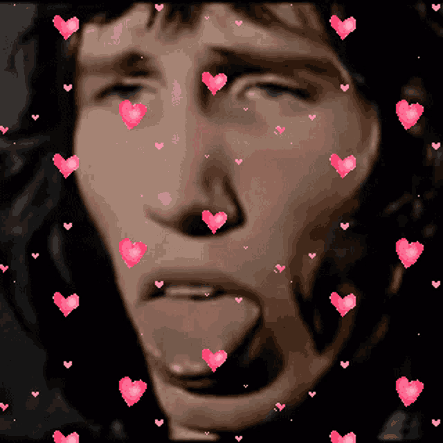 a man sticking his tongue out with pink hearts surrounding him