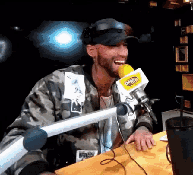 a man in a camo jacket is sitting at a table with a microphone that says ' 97.5 ' on it