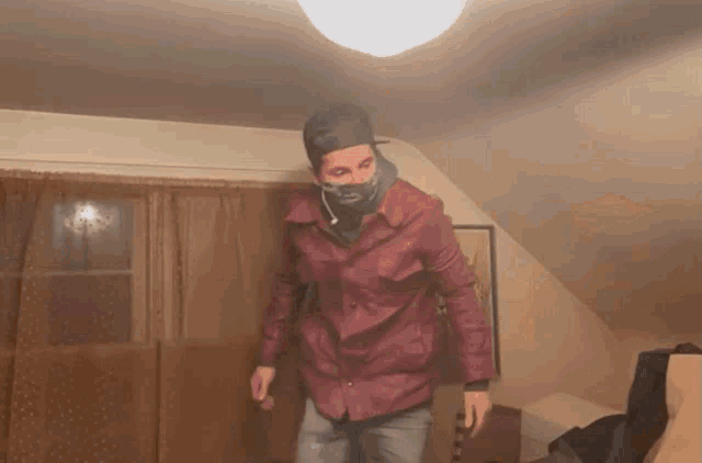 a man wearing a mask and a red shirt is dancing in a room