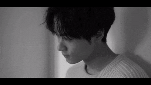 a black and white photo of a young man wearing a white sweater