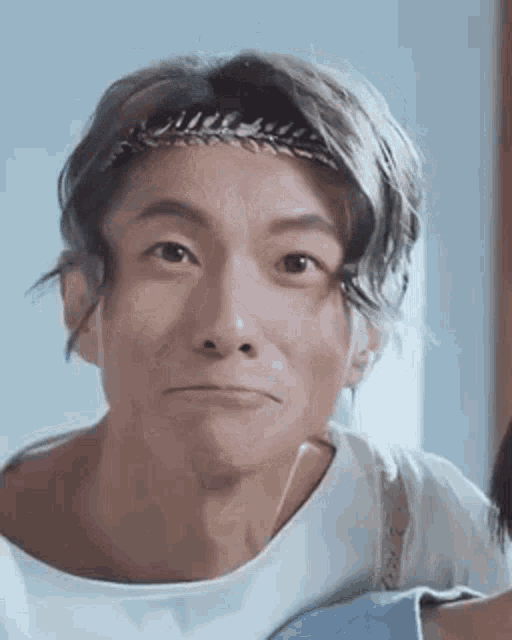 a close up of a man with a headband on his head making a funny face .